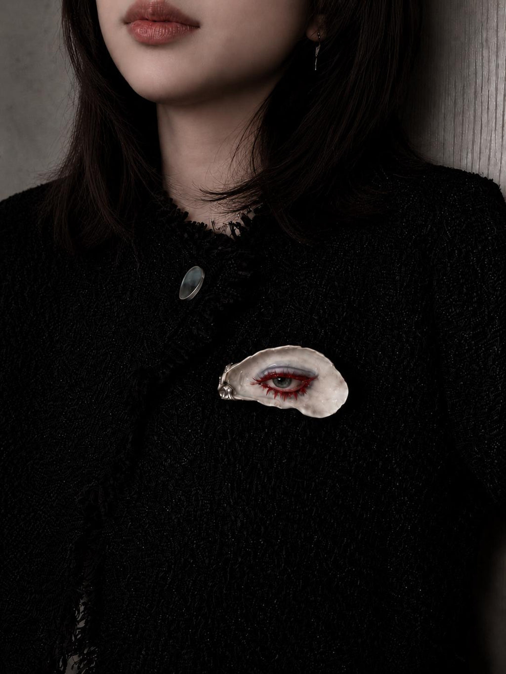 Red-Lash Oyster Eye brooch pinned to a black top.