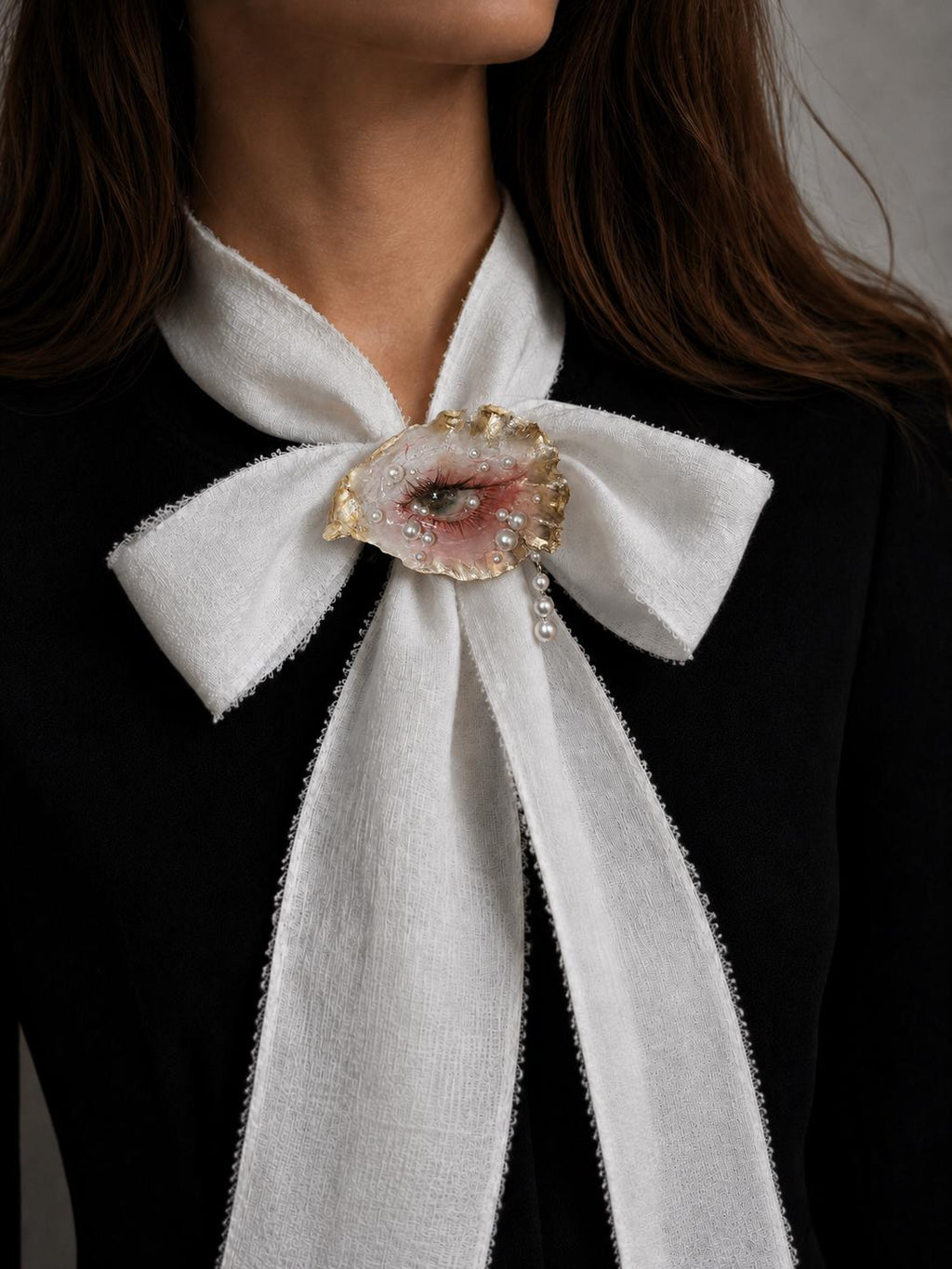 Gilded Oyster Eye worn at the center of a large ivory ribbon bow.