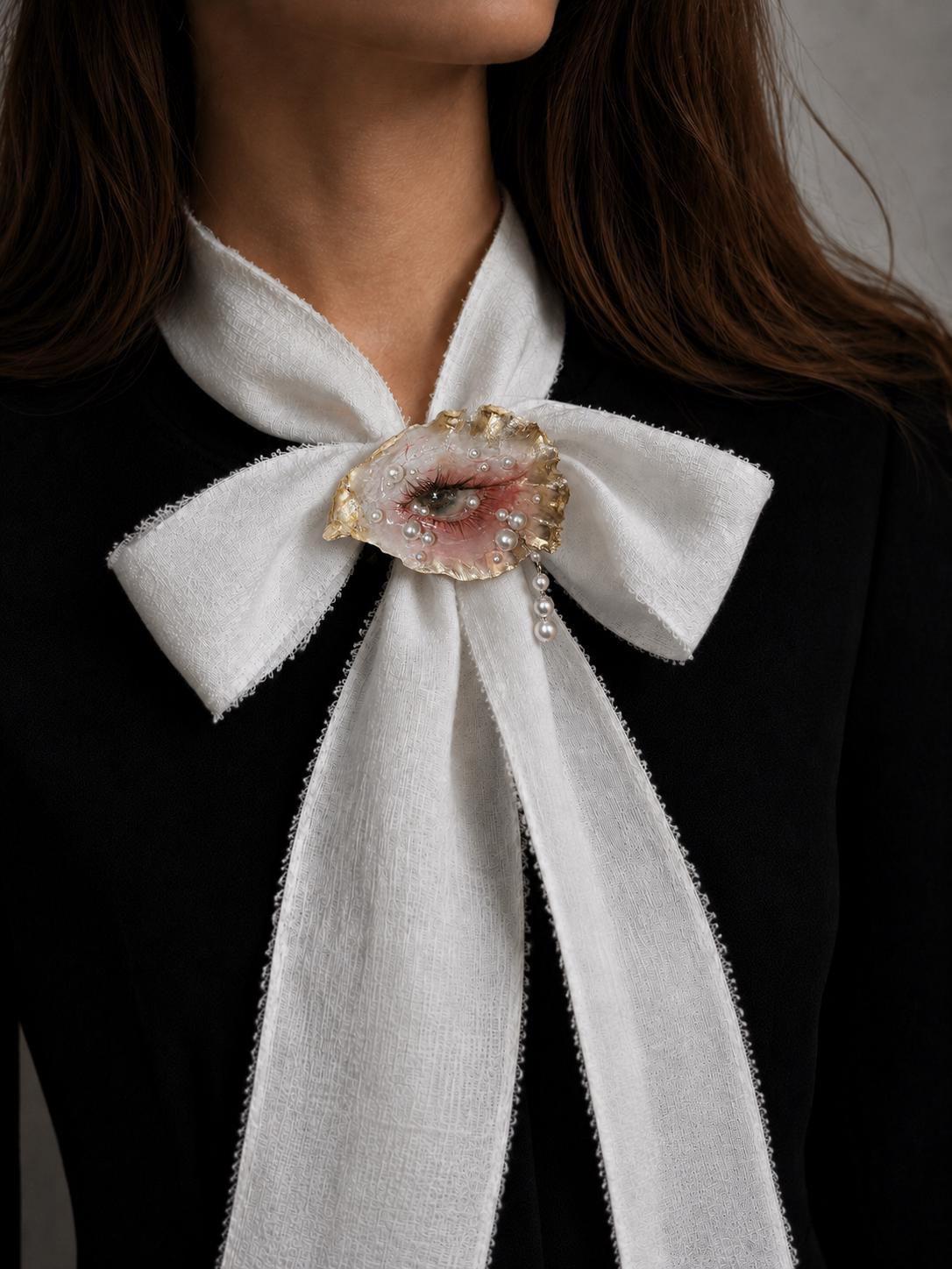 Gilded Oyster Eye worn at the center of a large ivory ribbon bow.