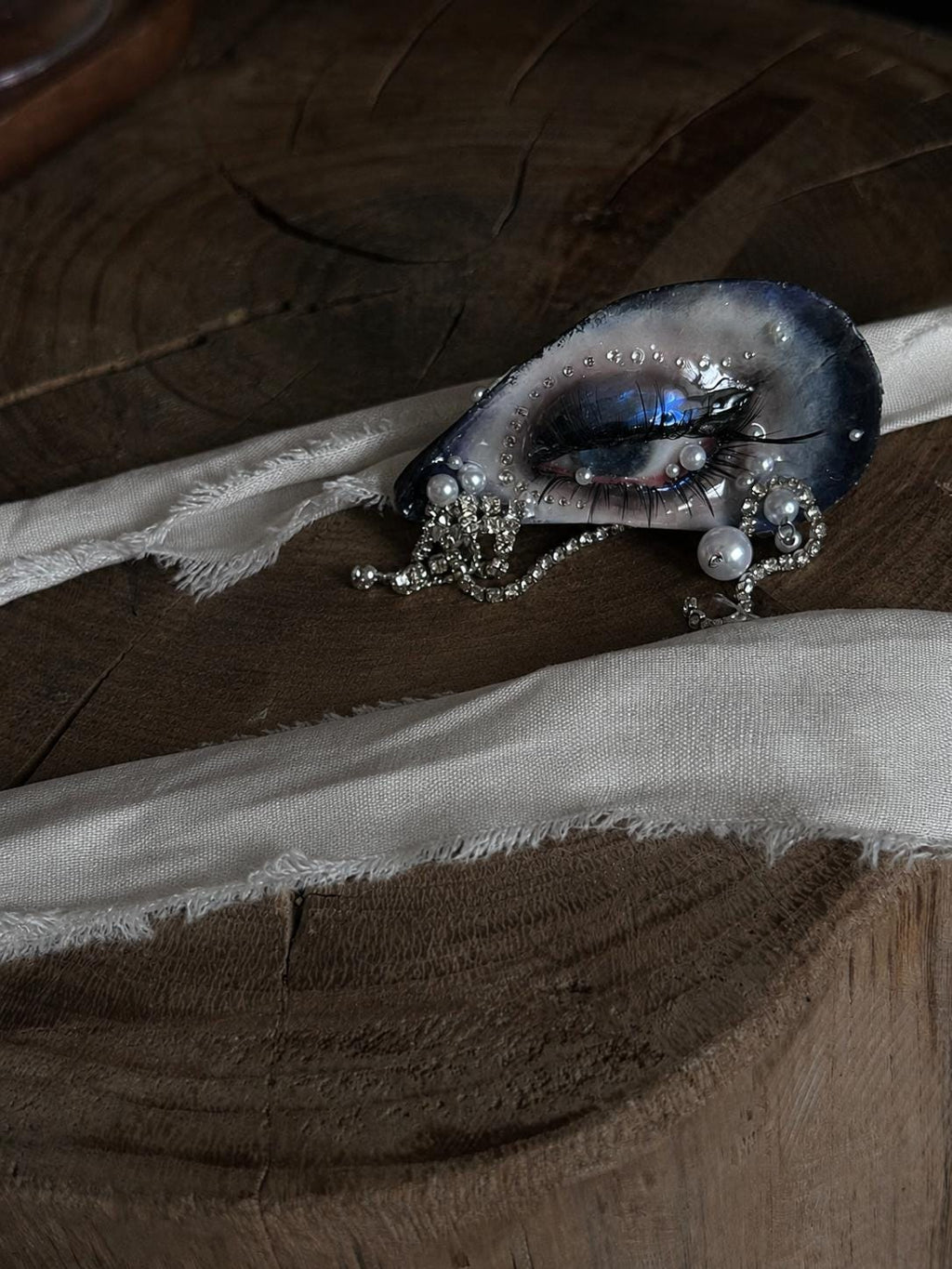 Blue Smoky Shell Eye displayed on pale ribbon over a wooden surface.