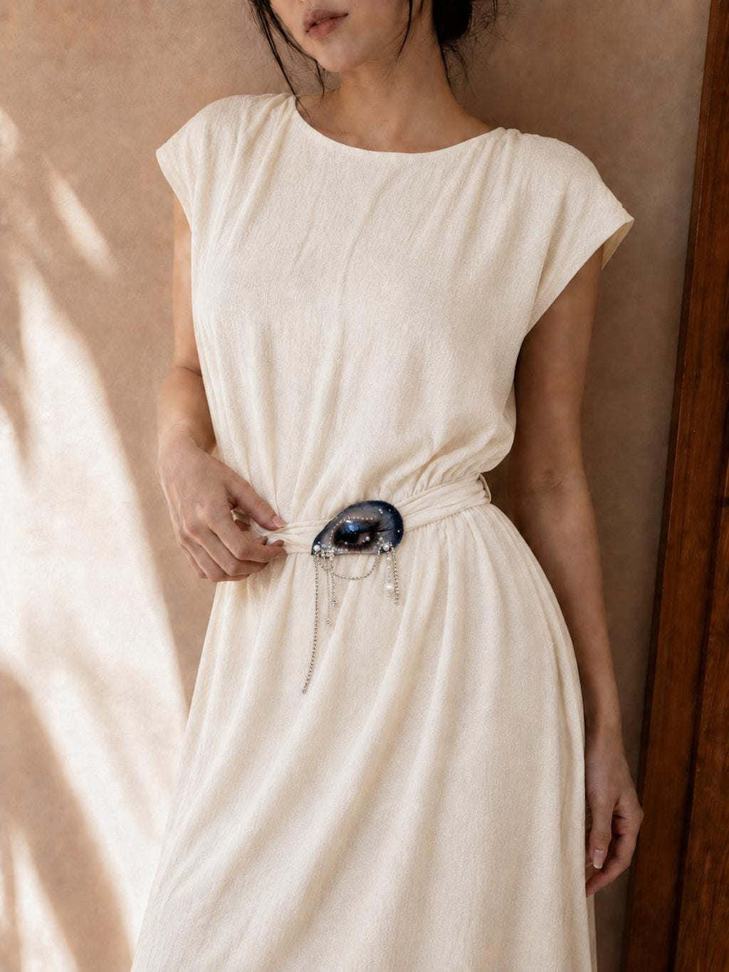 Blue Smoky Shell Eye worn at the waist of an ivory dress.