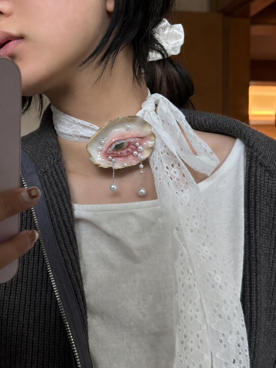 Green-and-Gold Oyster Eye worn as a white lace-ribbon choker.