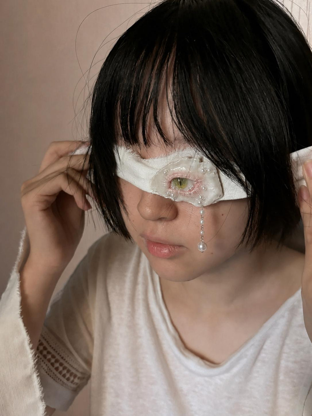 Cat-Eye Green Pupil shell-eye piece styled over one eye on a white fabric band.