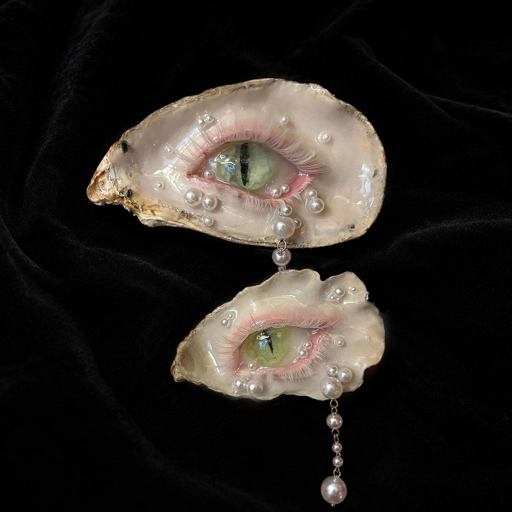 Two Cat-Eye Green Pupil shell-eye pieces shown at an angle on black velvet.