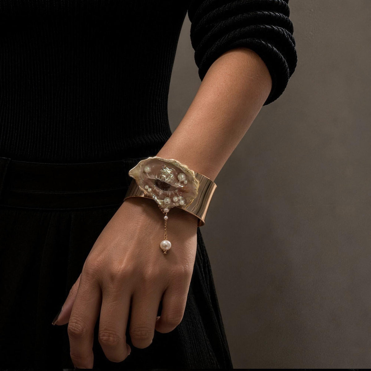 Gilded Oyster Eye Cuff Bracelet worn with a black sleeve.