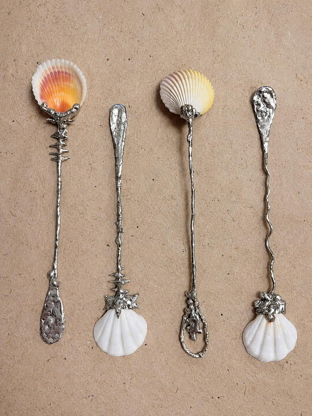 Three decorative shell spoons arranged side by side to show their bowl and handle designs.