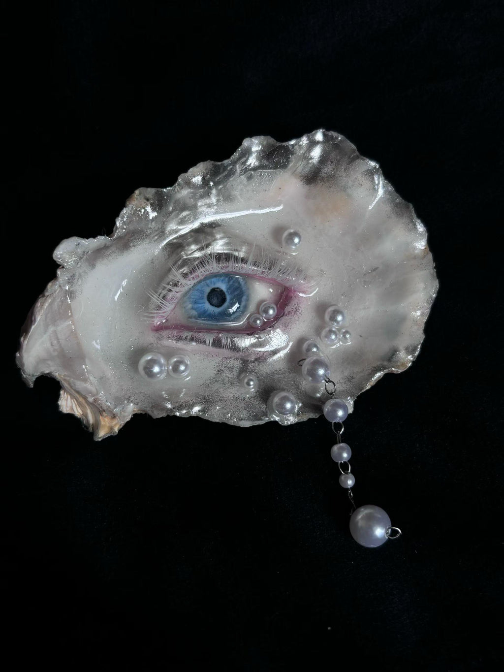 Pearl-Drop White-Water Blue Oyster Eye shown under cool lighting with a blue iris and hanging drop.