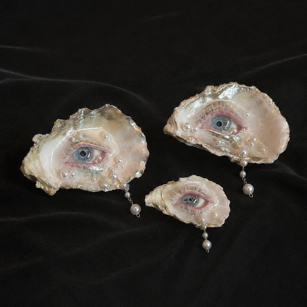 Three Pearl-Drop White-Water Blue Oyster Eye pieces in different sizes arranged on black velvet.