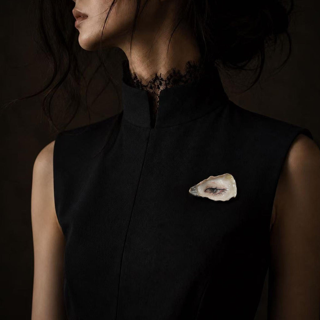 Nyra Black-Lash Oyster Eye brooch worn on a sleeveless black top.