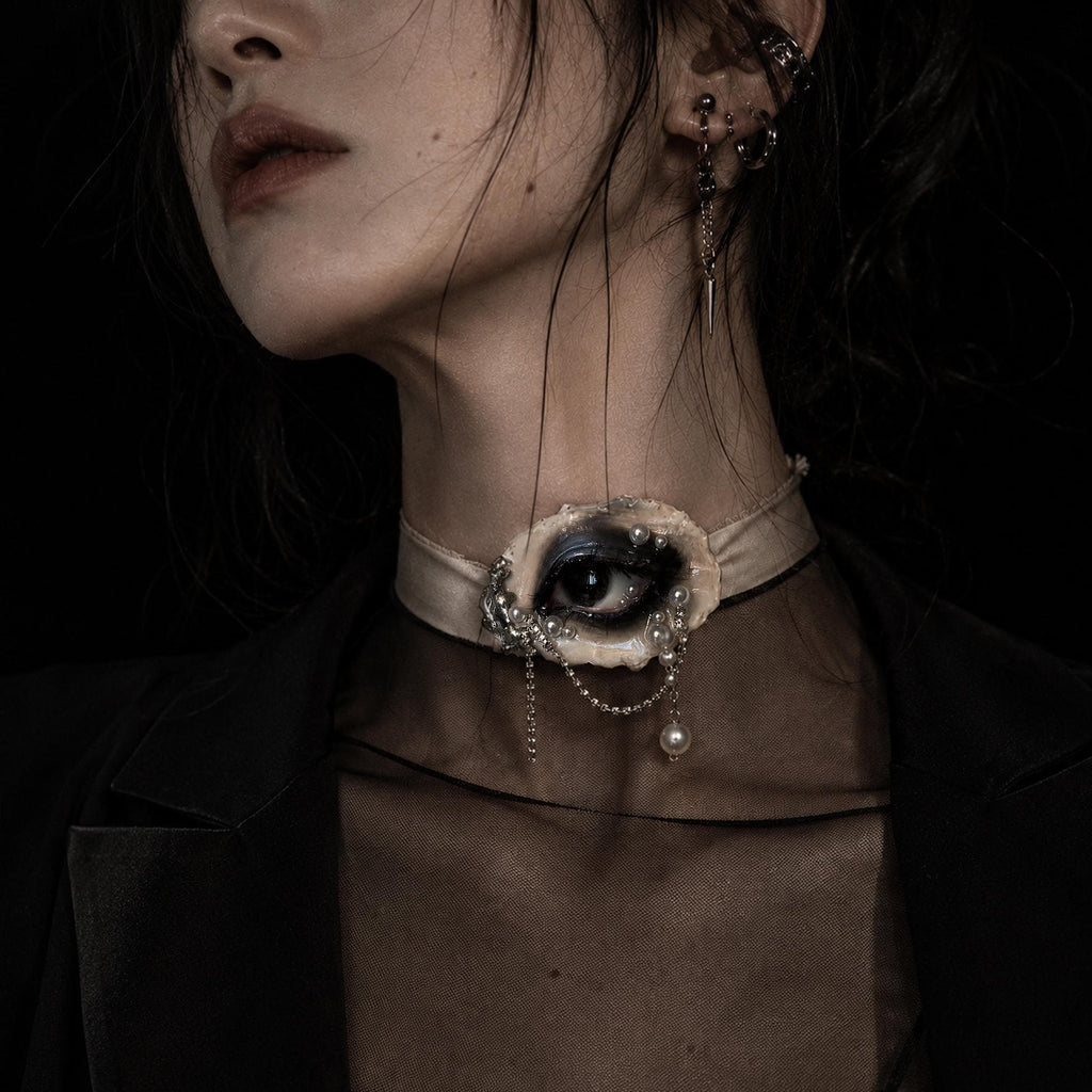 Lilith Veil Black Smoky oyster eye worn as an ivory-ribbon choker with a black blazer.