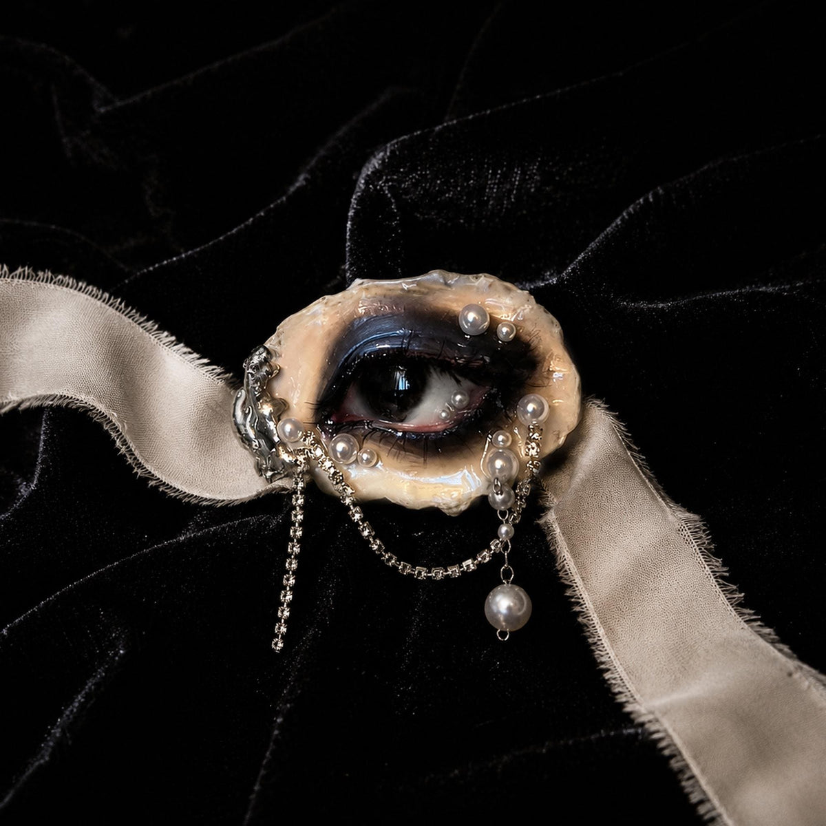Lilith Veil Black Smoky oyster eye displayed across ivory ribbon on black velvet.