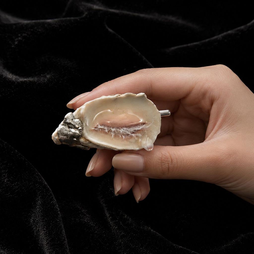 Nyra Sleeping Beauty shell-eye brooch held in a hand to show its scale.