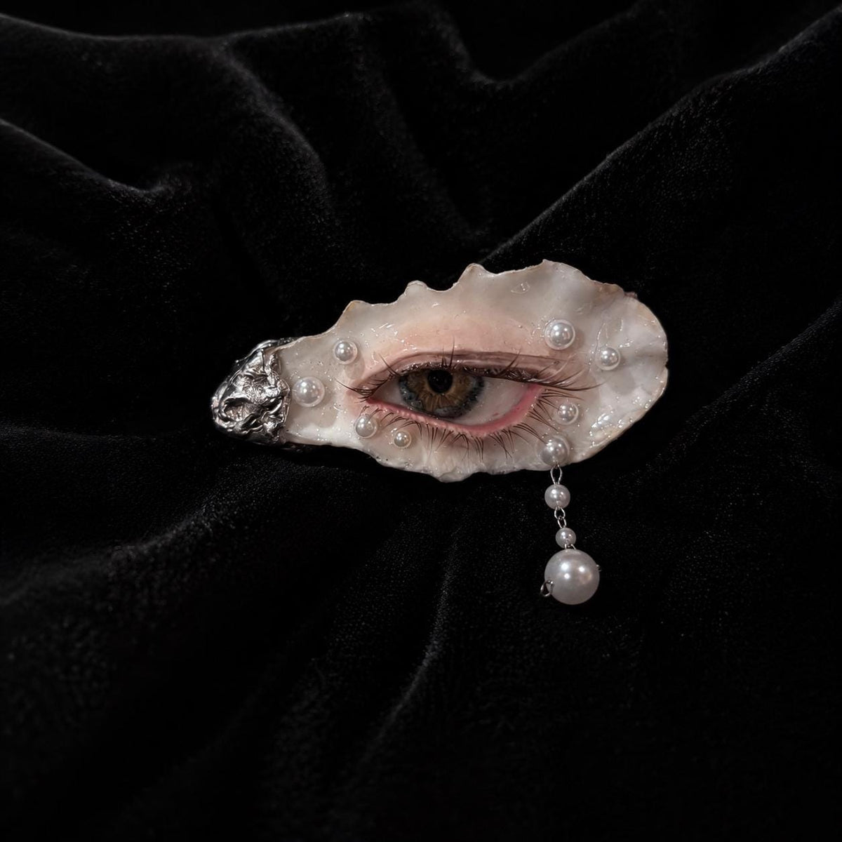 Nyra Halo Brown Eye shown from the front with a pink eyelid and hanging pearl-like detail.