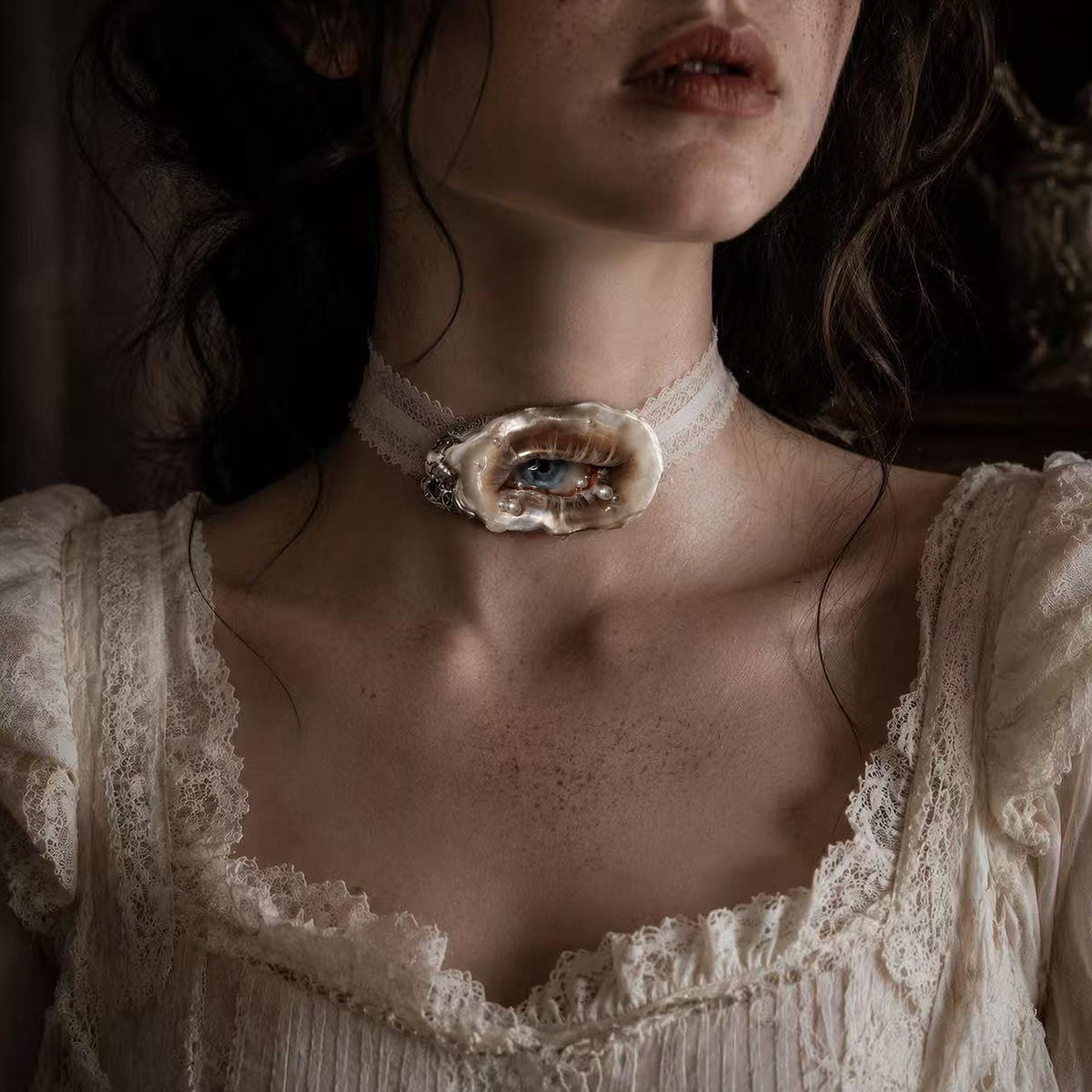 Lilith Veil Smoky Blue oyster eye worn as an ivory-ribbon choker.