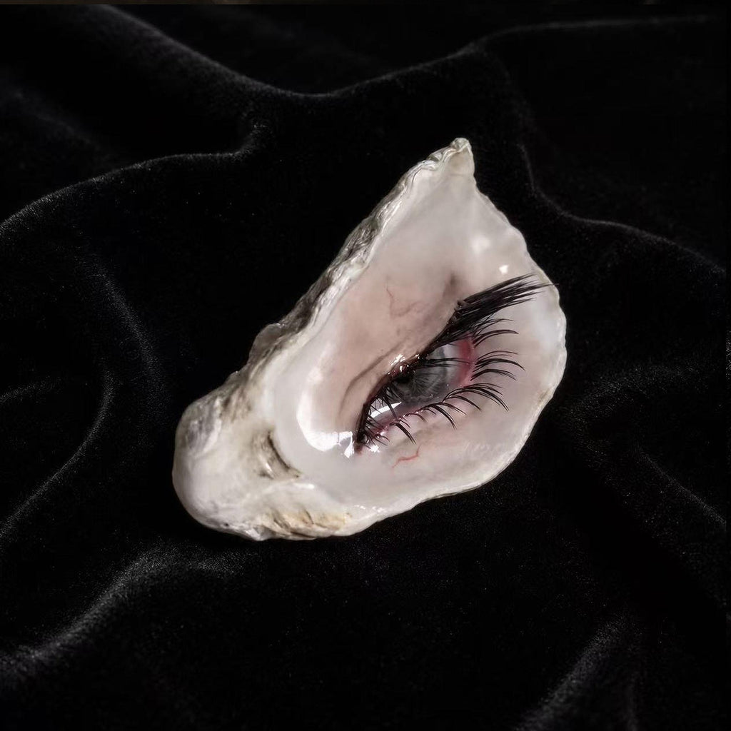 Angled view of Nyra Tender Gaze showing the pale shell and long dark lashes.