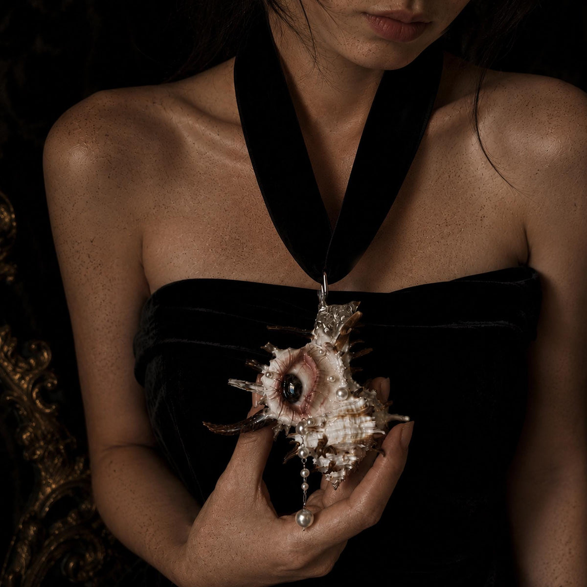 Abyss Guardians shell-eye necklace worn on black ribbon over a black dress.
