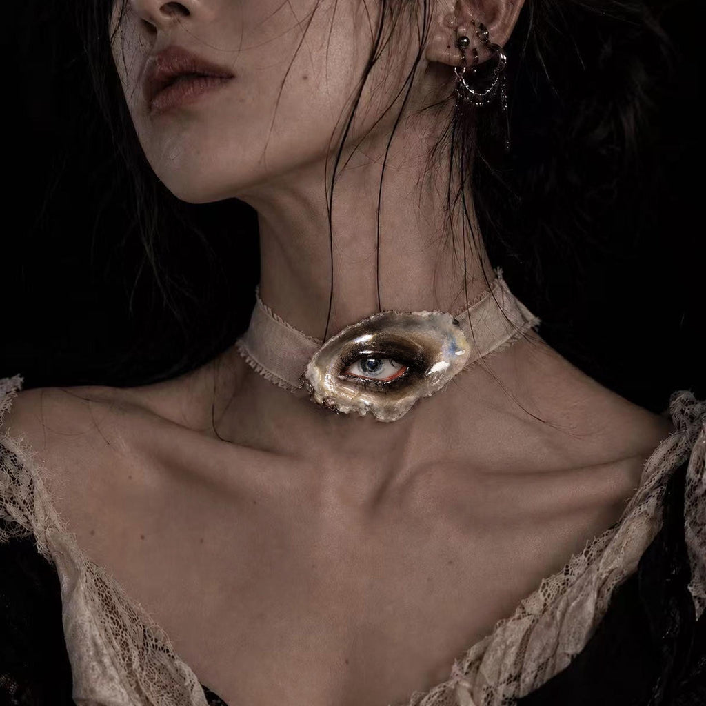 Lilith Grey Temptation oyster eye worn as an ivory-ribbon choker.
