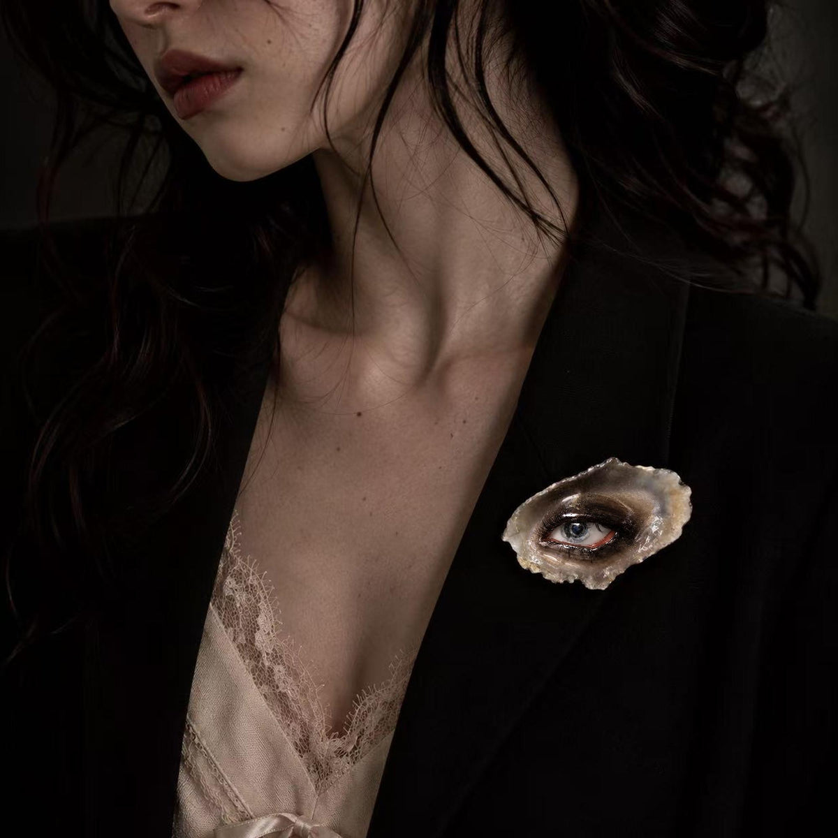 Lilith Grey Temptation shell-eye brooch worn on a dark blazer.