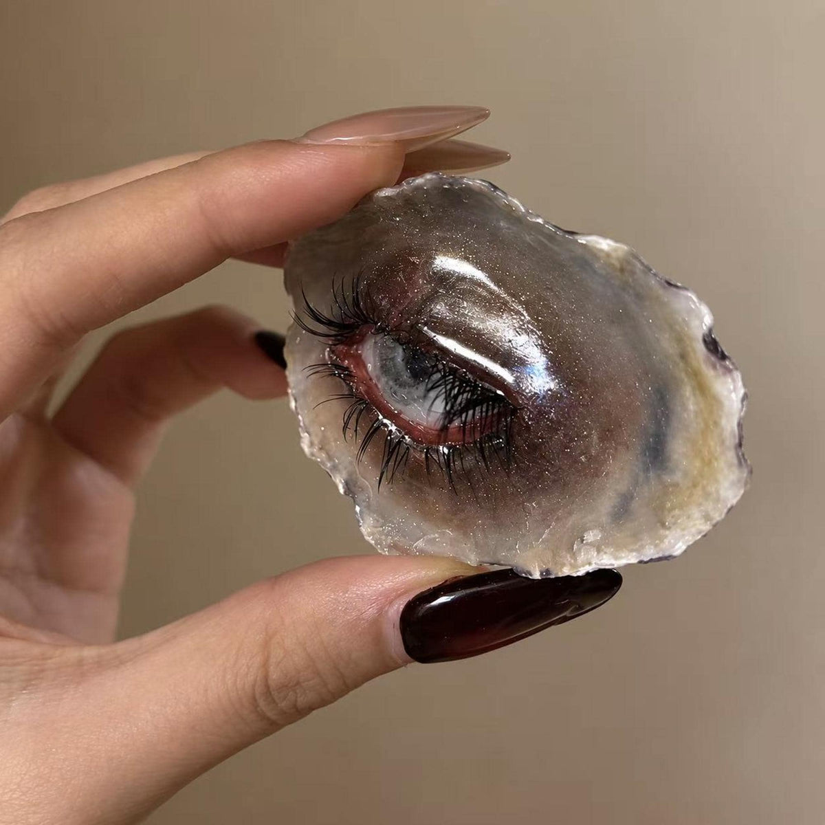Angled hand-held view of Lilith Grey Temptation showing the sculpted eyelid and shell depth.
