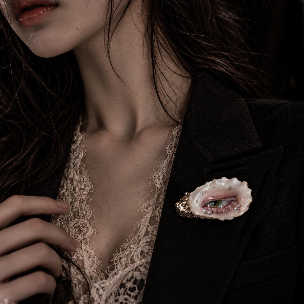 Nyra Nacre Veil shell-eye brooch worn on a dark blazer over an ivory blouse.
