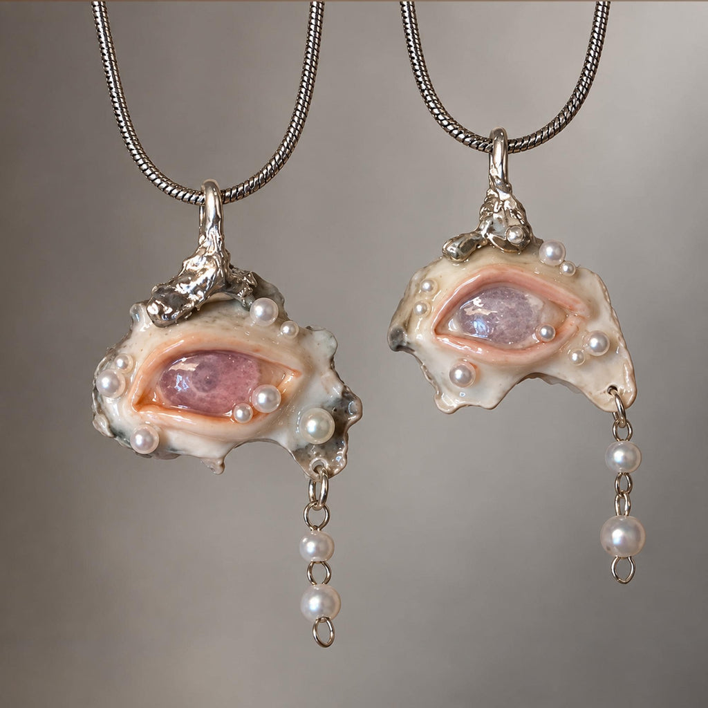 Two Nyra shell-eye pendants in different colors hanging from fine metal chains.