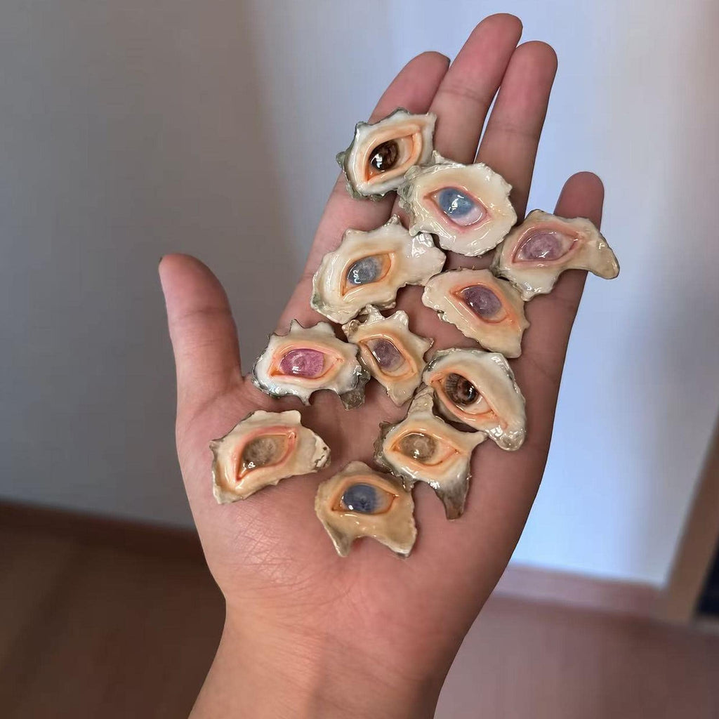 Assortment of small shell-eye pieces with different iris colors displayed across a palm.